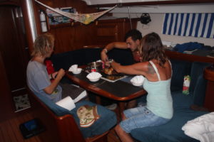 Tre personer sitter runt ett bord på en båt och äter.