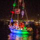 En segelbåt går för motor på natten och är helt belamrad av julbelysning.
